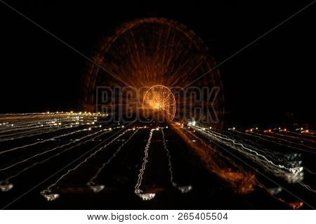 Ferris Wheel At Night With A Motion Blur, Zoom In, Zoom Out Effect, Yellow Golden Light, Amusement P