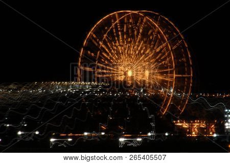 Ferris Wheel At Night With A Motion Blur, Zoom In, Zoom Out Effect, Yellow Golden Light, Amusement P