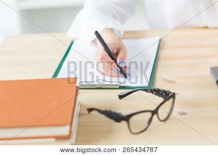 Planning Concept - Close Up Of Woman Sitting At Her Desk And Making Notes In A Notebook