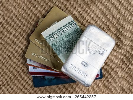 Cash Dollars And Plastic Cards And Silver Bullion Against The Background Of Coarse Cloth. Silber Is 