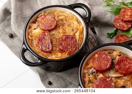 Slovak Christmas Cabbage Soup In Two Small Pots With Sausage On The Top On White Background.