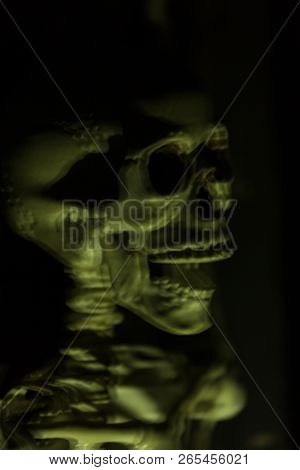 Skeleton Hanging In The Darkness Ready To Scare People. Intentional Motion Blur To Convey Movement A