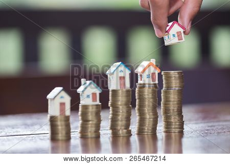 Woman Hand Hold A  Home Model Put On The Stack Coin With Growing, Savings Money For Buy House And Lo