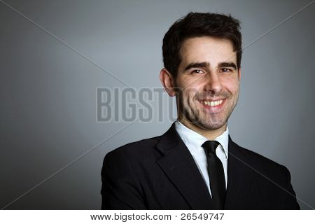 Retrato de primer plano de un hombre de negocios joven guapo en fondo gris