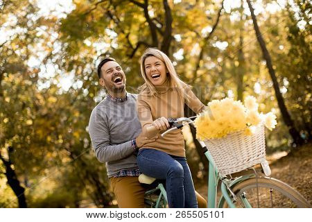 Active Young Couple Enjoying Riding Bicycle In Golden Autumn Park