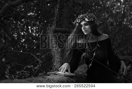Beautiful Young Halloween Witch Wearing Vintage Gothic Dress And Holding Magical Book.