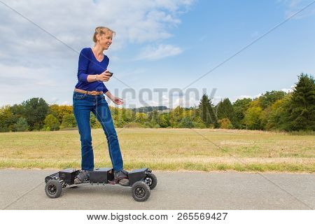Caucasian Woman Rides Electrical Mountainboard On Road In Nature