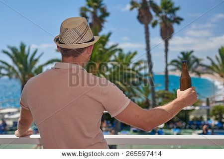Bristled Man With A Sun Hat Relaxing With The Bottle Of Beer While Being On Vacation. Santa Susanna.