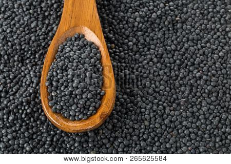 Heap Of Black Organic Beluga Lentils In Wooden Spoon On Black Beluga Lentil Background