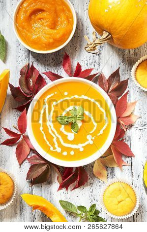 Pumpkin Soup And Muffins With The Dry Autumn Leaves On White Wooden Background