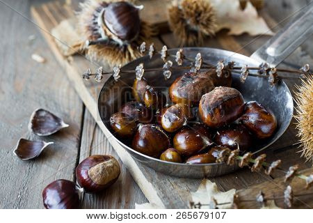 Roasted Chestnuts In Cast Iron Grilling Pan Over Rustic Wooden Board Background, Selective Focus, Ro