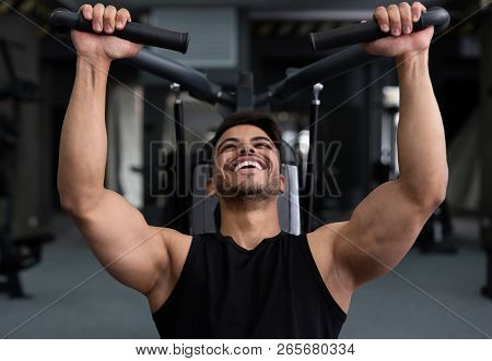 Arab Man Training Hard At Gym, Doing Workout On Fitness Machine