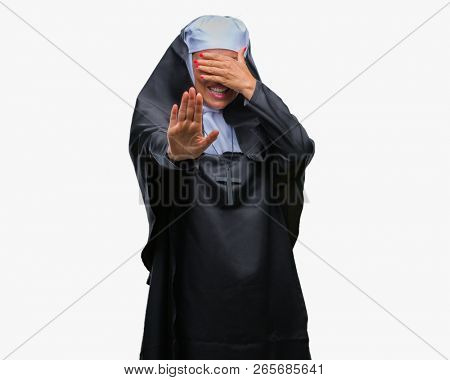 Middle age senior christian catholic nun woman over isolated background covering eyes with hands and doing stop gesture with sad and fear expression. Embarrassed and negative concept.