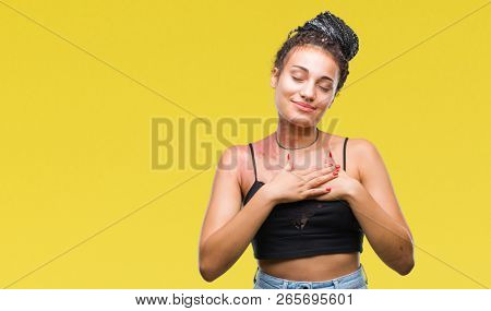 Young braided hair african american with pigmentation blemish birth mark over isolated background smiling with hands on chest with closed eyes and grateful gesture on face. Health concept.