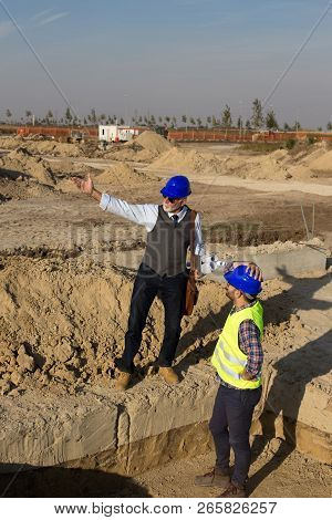 Senior Architect Explaining Project To A Younger Construction Worker At Building Site