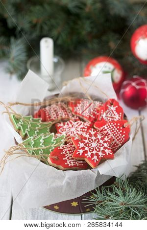 Gingerbread In A Tin Box In The Background With Christmas Toys, A Candle And Fir Branches.