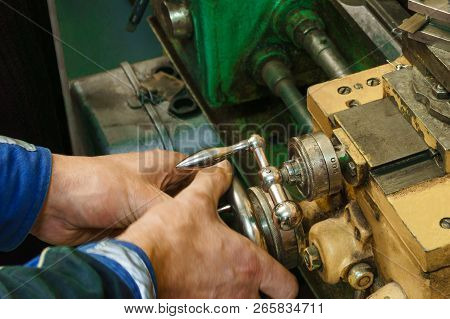 Working On Turnind Lathe With Manual Control, Hands Of Turner Hold The Handles Of The Carriage
