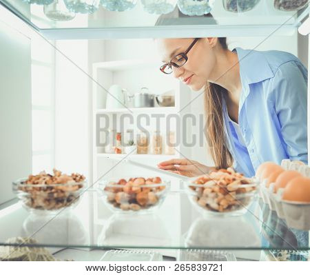 Portrait of female standing near open fridge full of healthy food, vegetables and fruits. Portrait of female
