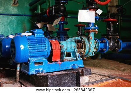 Old, Rusty Scratches Water Pump With An Electric Motor Dyed In Blue Color On The Cold Water Pipe.