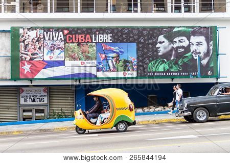 Havana, Cuba - Feb 21, 2016: Coco Taxi And A Propagandistic Poster In Vedado Neighborhood Of Havana.