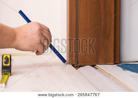 Construcion Worker Measuring Floor Panels Using Ruler And Pencil. Home Renovation Concept.