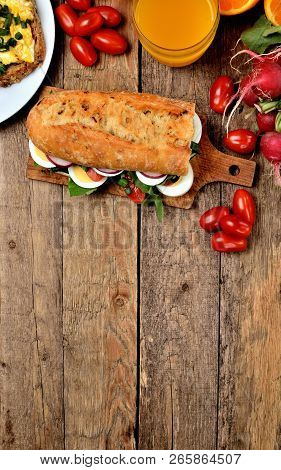 View From Above Of Baguette Sandwich With Egg, Arugula Salad, Tomatoes And Radish