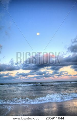 Moonset Over The Ocean At Vanderbilt Beach At Sunset