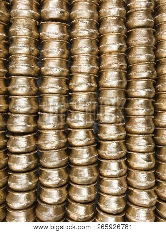 Huge pile of neatly stacked small gold- painted earthen pots. Close up of handmade bowls are displayed in the market in rural India. 