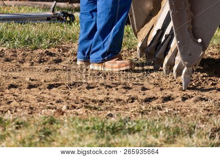 Abstract of Worker Standing Near Small Bulldozer Bucket At Constrcution Site