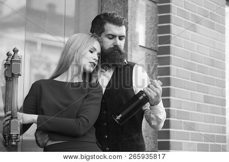 Couple In Love Looking At Bottle Of Wine. Man Or Hipster Hugging Sexy Woman Or Girl In Blue Dress Ou