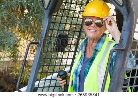 Smiling Female Worker Using Small Bulldozer At Constrcution Site