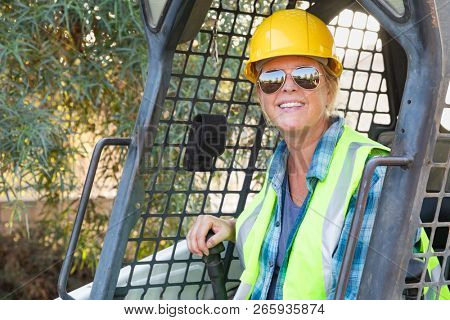 Smiling Female Worker Using Small Bulldozer At Constrcution Site