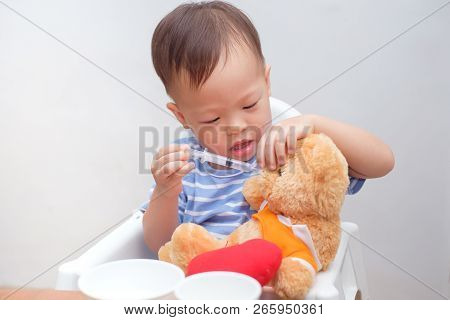 Cute Little Asian 2 Years Old Toddler Baby Boy Child Playing Feeding Teddy Bear With Liquid Medicine