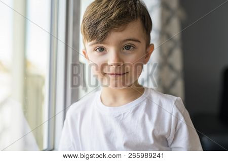 The Nice And Beautiful Boy Stands Near To A Window