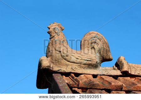 Worn Down Dilapidated Edge Roof Tile Shaped Like Sitting Rooster Overlooking Surroundings With Clear