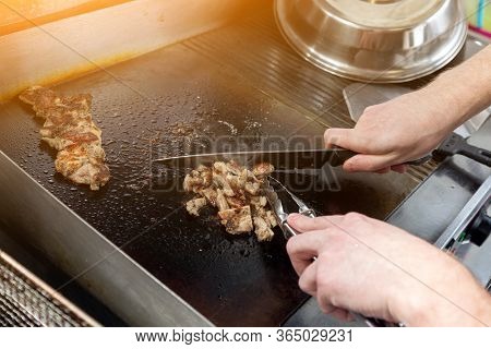 Step By Step Cooking Chicken: A Man In An Apron Cuts Slices With A Knife On A  Glove. Cooking Burrit