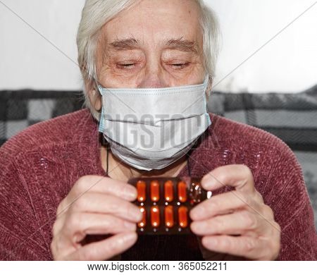Elderly Woman In A Medical Mask. The Tablets