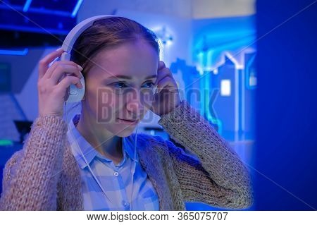 Woman Looking At Exposition, Using White Headphones And Listening Audio Guide At Modern Futuristic E