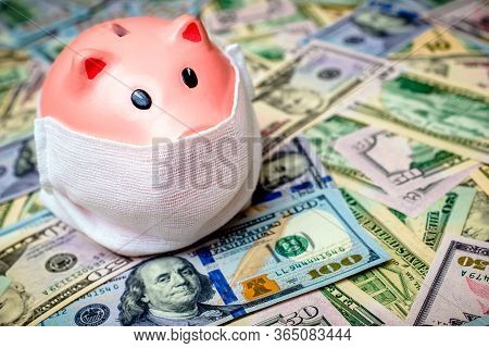 Piggy Bank In A Mask On A Background Of American Currency.the Concept Of Coronavrius Epidemic