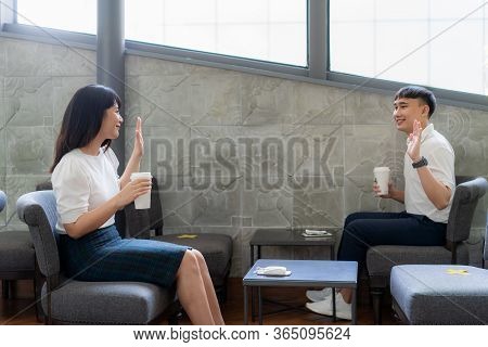 Asian Young Man And Woman Sitting One Person Per One Table And Greet And Say Hello For Distance Of 6