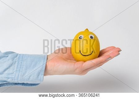 Funny Lemon-smiley With Googly Eyes Lying On Palm On White Background.