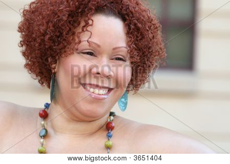 Mujer con cabello rizado rojo y joyas brillantes