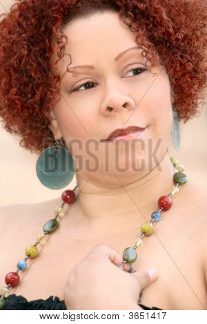 Mujer con cabello rizado rojo y joyas brillantes