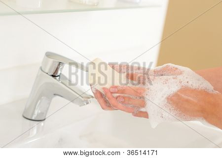 Primer plano de lavarse las manos con jabón sobre el lavabo del baño