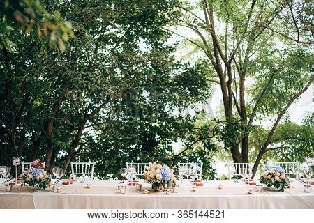 Wedding Dinner Table Reception. A Bouquet Of Pink Roses And Blue Hydrangeas Is On The Table In A Vas