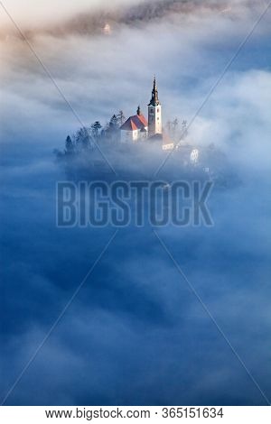 amazing panorama of Lake Bled Blejsko Jezero on a foggy morning with the Pilgrimage Church of the Assumption of Maria on a small island and Bled Castle and Julian Alps in backgroud