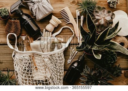 Collection of various succulent plants and Mesh market bag with bamboo cutlery, reusable bottles and eco cotton bags on wooden background
