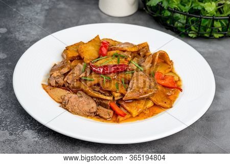 Braised Beef With Potatoes In A White Plate On A Gray Background