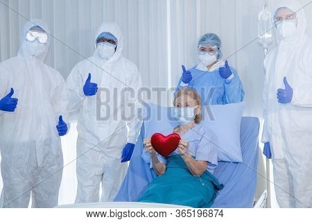 Old Woman Patient Hold Mini Heart On A Wheelchair With Background Of The Medical Team Thumbs Up Afte