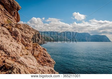 Rocky Coast, Blue Sea And Sky With White Clouds